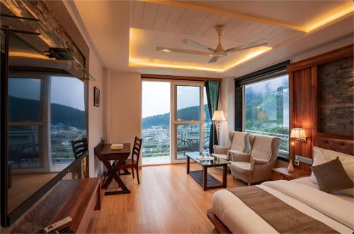 a hotel room with a bed and a chair and windows at Jr Hotel Dharamshala in Dharamshala