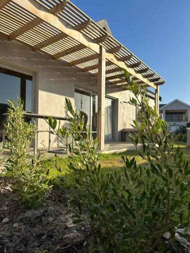 a house with a wooden pergola in a yard at Sandown Synergy Lagoon House in Hermanus