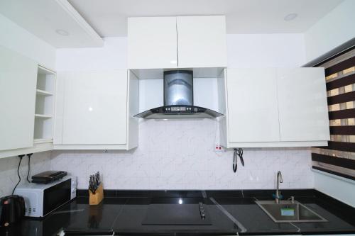 a kitchen with white cabinets and a sink at Fort Fountain Apartments in Abuja