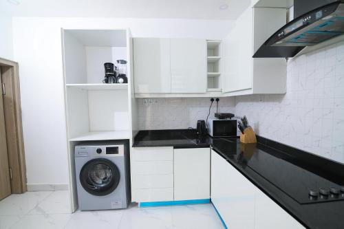 a white kitchen with a washing machine in it at Fort Fountain Apartments in Abuja