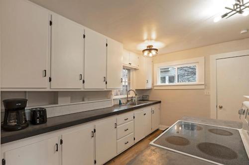 a kitchen with white cabinets and a sink at Slant Streets Bungalow in Missoula