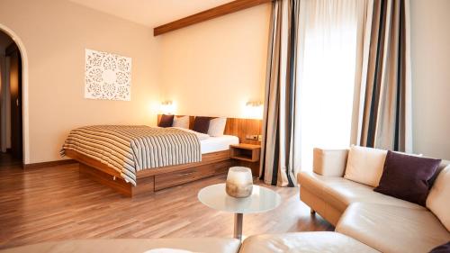 a hotel room with a bed and a couch at Hotel Bavaria - Partnerbetrieb von Oberstaufen PLUS in Oberstaufen