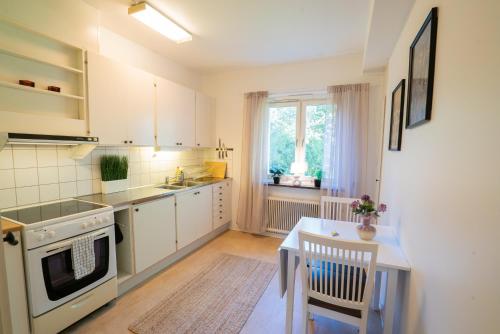 a kitchen with white cabinets and a table and a window at Central Studio, Near City & Tram - Brämaregården in Gothenburg