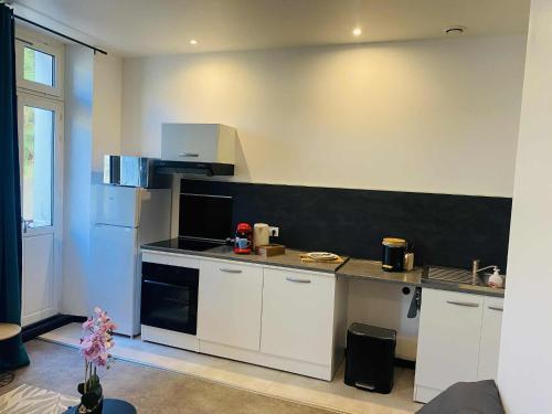 a kitchen with white cabinets and a black counter top at Charmant T2 centre ville N 4 in Marmande