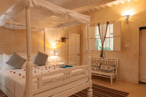 a bedroom with a white bed with a canopy at Banana House and Wellness Centre in Lamu