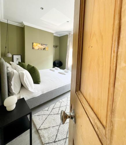 a bedroom with a bed with white sheets and green walls at Rodney Retreat, Ramsgate Kent in Haywards Heath