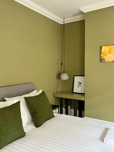 a bedroom with a bed with green walls and a table at Rodney Retreat, Ramsgate Kent in Haywards Heath