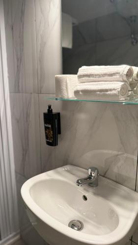 a bathroom with a sink and towels on a shelf at B&B Bella Mare Suites - Formia in Formia