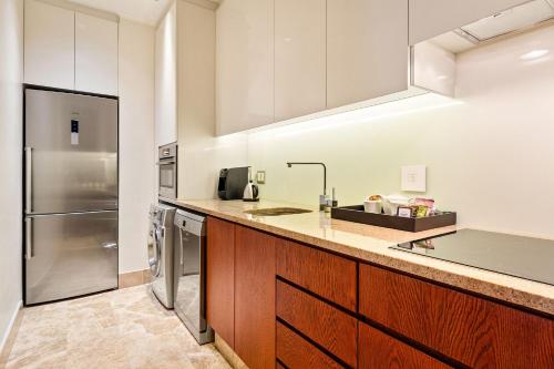 a kitchen with wooden cabinets and a stainless steel refrigerator at Taj Hotel 305 by Host Agents in Cape Town