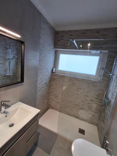 a bathroom with a shower and a sink and a window at Casa R in Sesimbra