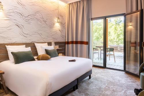 a bedroom with a large white bed and a balcony at Mercure Ax Les Thermes in Ax-les-Thermes