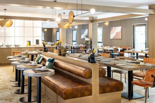 a restaurant with a leather bench and tables at Mercure Ax Les Thermes in Ax-les-Thermes