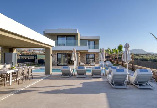 a patio with chairs and umbrellas next to a pool at Divel Luxury Villas with heated pools, by Estia in Anissaras
