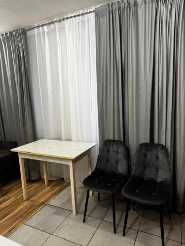 een tafel en twee stoelen voor een raam bij Апартаменты в центре города in Chişinău