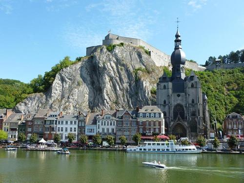 a large building with a church next to a body of water at Studio 50m from the Citadel in Dinant