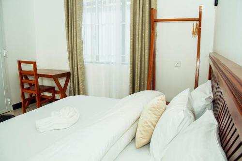 a bedroom with a bed with white sheets and a chair at Maasai Villa in Arusha