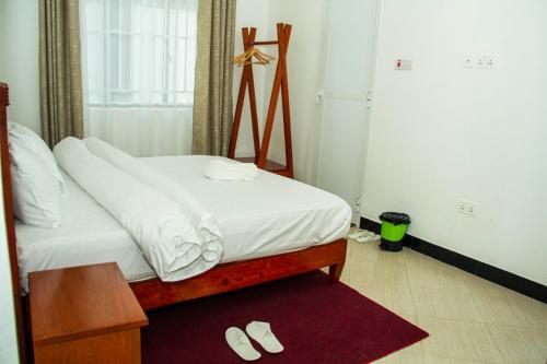 a bedroom with a bed with white sheets and slippers at Maasai Villa in Arusha
