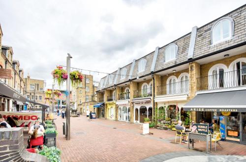 eine Straße mit Gebäuden und Menschen, die auf einem Bürgersteig sitzen in der Unterkunft Stunning Apartment -Quick Access to Central London in Ealing