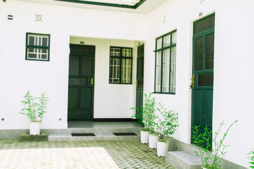 a white house with black doors and potted plants at Maasai Villa in Arusha