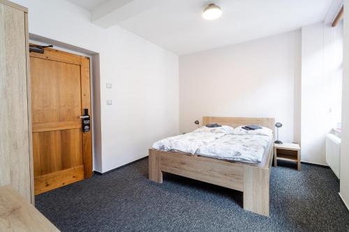 a bedroom with a bed and a wooden door at Pivovar Prachatice in Prachatice