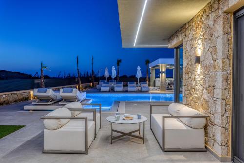a patio with white furniture and a pool at night at Divel Luxury Villas with heated pools, by Estia in Anissaras