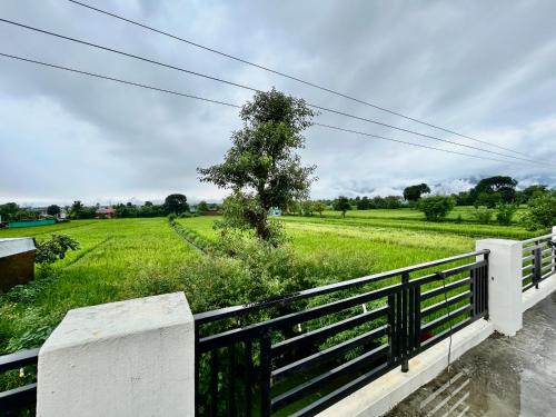 a view of a field with a fence and a tree at Athulyam Homes in Dehradun