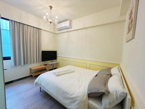 Un dormitorio con una cama y un televisor de pantalla plana. en 巴洛克文旅 #海安藝術街#神農街住宿#花園夜市民宿推薦, en Tainan