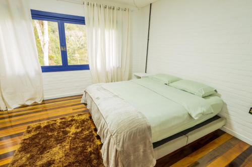 a bedroom with a bed and a window and a rug at Sitio Dona Bela - Rio da Prata in Joinville