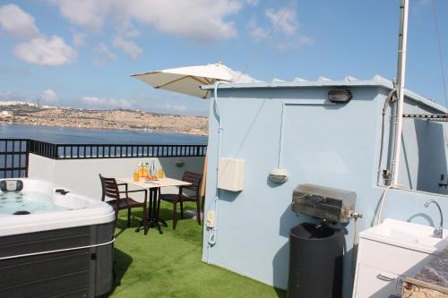 a small balcony with a table and a grill at Islet Promenade Studio with Hot Tub and Panoramic Sea Views by GetawaysMalta in St. Paul's Bay