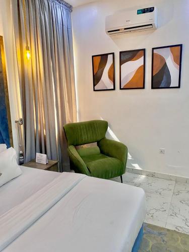 a bedroom with a bed and a green chair at Fort Fountain Apartments in Abuja