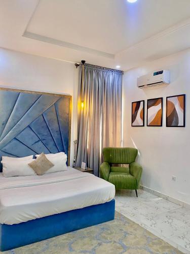a bedroom with a bed and a green chair at Fort Fountain Apartments in Abuja