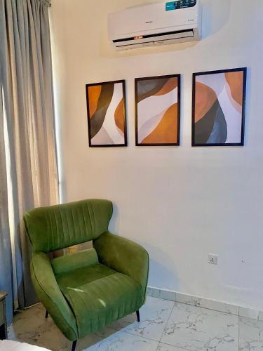 a green chair in a room with four pictures on the wall at Fort Fountain Apartments in Abuja