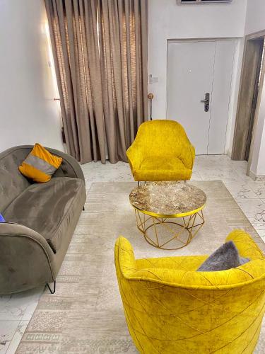 a living room with a couch and a yellow chair at Fort Fountain Apartments in Abuja