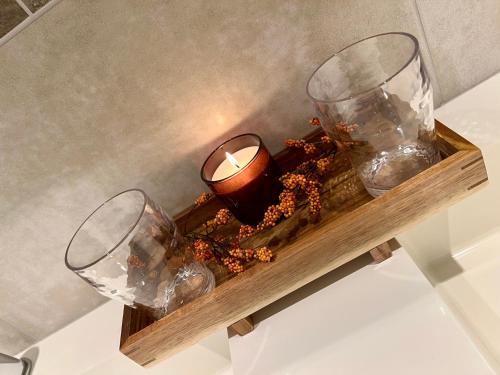two glasses and a candle on a wooden shelf at Hybel i underetasje 700m fra strand in Trøgstad