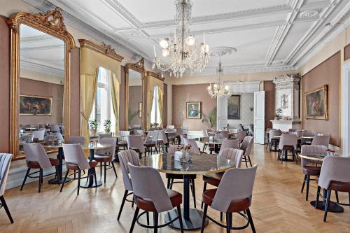 Un comedor con mesas y sillas y una lámpara de araña. en Karlskrona Stadshotell, Best Western Signature Collection, en Karlskrona