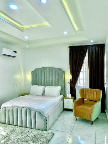 a bedroom with a large bed and a chair at Fort Fountain Apartments in Abuja