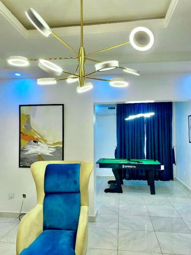a living room with a ping pong table and a blue chair at Fort Fountain Apartments in Abuja