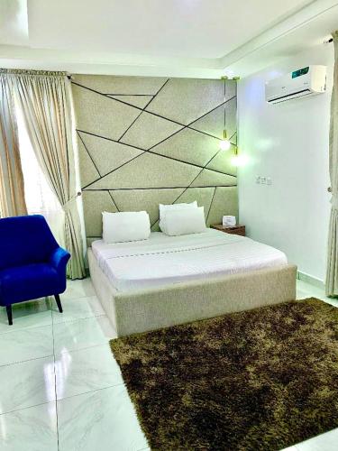 a bedroom with a bed and a blue chair at Fort Fountain Apartments in Abuja
