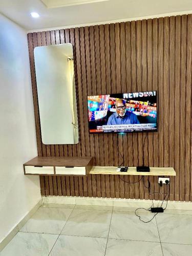 a television on a wooden wall with a mirror at Fort Fountain Apartments in Abuja