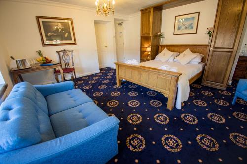 a bedroom with a bed and a blue couch at Santo's Higham Farm Hotel in Alfreton