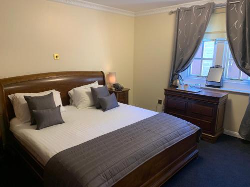 a bedroom with a bed and a desk and a window at Santo's Higham Farm Hotel in Alfreton