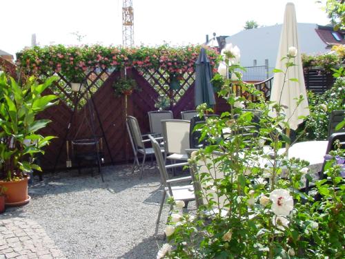 a patio with chairs and an umbrella and flowers at Pension Pieschen Dresden in Dresden