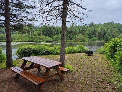 a wooden picnic table sitting next to a lake at Spa & Lake Access - The Lakeshore in Rawdon