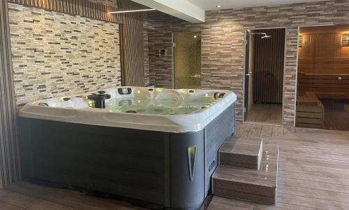 a jacuzzi tub in a bathroom with a brick wall at Hotel Magnific in Kranevo