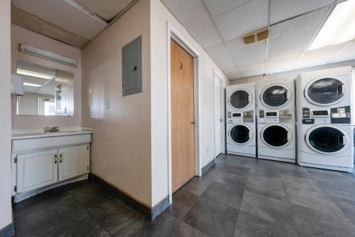 a laundry room with three washing machines and a counter at King City Motel by OYO Pasco in Pasco