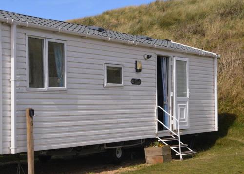 a white trailer with a door on a hill at Anchor Park in Happisburgh