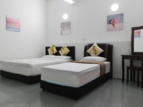 two beds in a room with a desk at KG Hotel in Kampong Sorosob