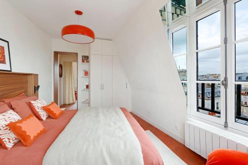 a bedroom with a bed with orange and white pillows at la suite rouge du marais in Paris
