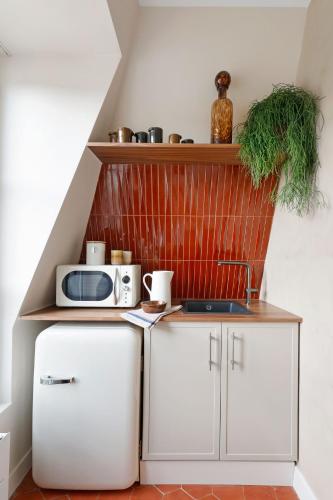 une cuisine avec des armoires blanches et un micro-ondes dans l'établissement la suite rouge du marais, à Paris