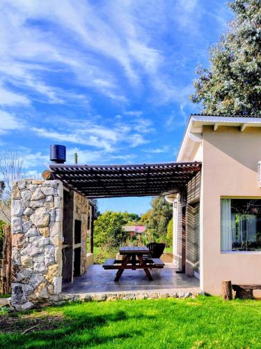 a patio with a picnic table and a stone wall at Casas del Arroyo in Chapadmalal